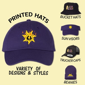 May include: A variety of printed hats in different styles, including bucket hats, sun visors, trucker caps, and beanies. The hats feature a purple color and various designs, including a sun with a silhouette of a couple inside, and the text "I'm the Lost Princess".