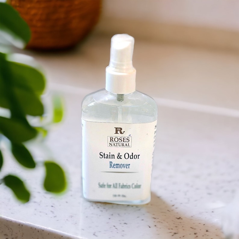 May include: A clear spray bottle with a white label that reads "Roses Natural Stain & Odour Remover. Safe for All Fabrics & Colours."