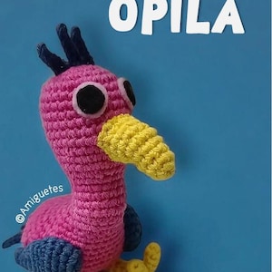 Puede incluir: Un pájaro de crochet rosa con un pico amarillo y alas azules. El pájaro está sentado sobre un fondo azul. El texto "OPILA BIRD" está escrito en letras blancas sobre el fondo.