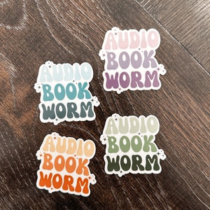 May include: Four colorful stickers with the text "Audio Book Worm" in a retro font. Each sticker has a different color scheme, with shades of pink, purple, blue, green, and orange.