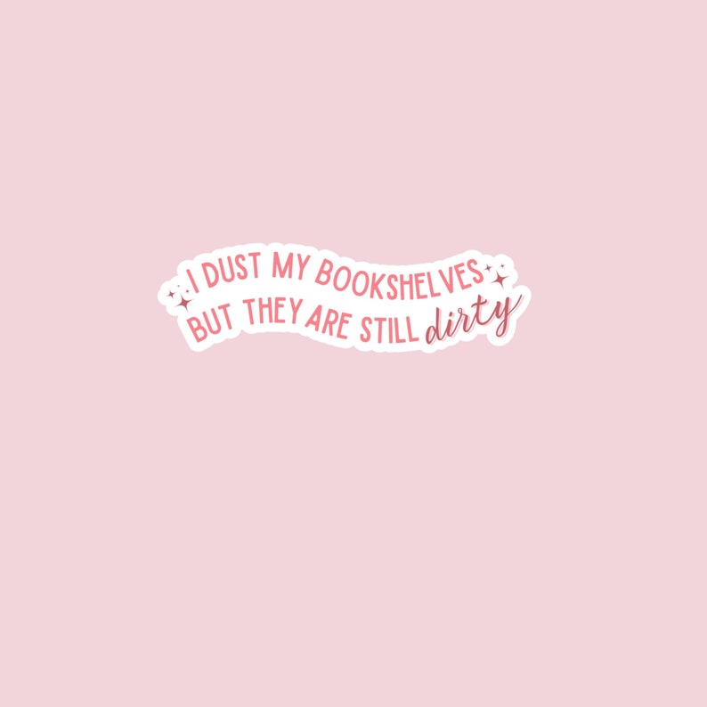 May include: Pink sticker with the text "I dust my bookshelves but they are still dirty" in a white outline with pink stars on either side.