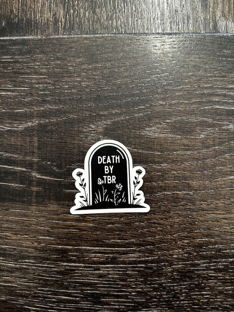 May include: Black and white sticker of a tombstone with the text "DEATH BY TBR" and flowers.