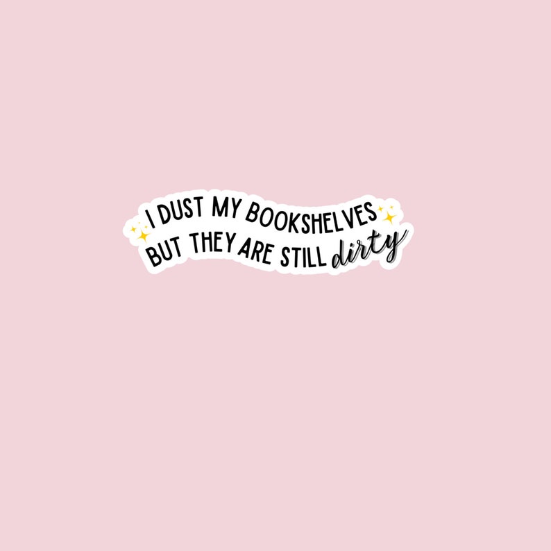 May include: A white sticker with black text that reads "I dust my bookshelves but they are still dirty". The text is curved and has a few small yellow stars on either side.
