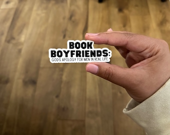 May include: A white sticker with black text that reads "BOOK BOYFRIENDS: GOD'S APOLOGY FOR MEN IN REAL LIFE."