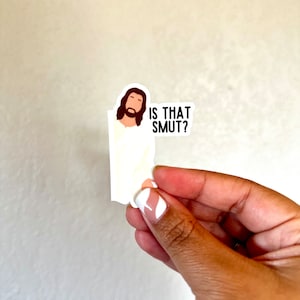 Op de afbeelding: Een witte sticker met een cartoonafbeelding van Jezus en de tekst "IS THAT SMUT?"