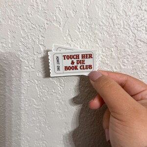K&ouml;nnte beinhalten: Ein wei&szlig;es Ticket mit rotem Text, auf dem "Touch Her & Die Book Club" und "Admit One" steht, das an der Seite gedruckt ist.