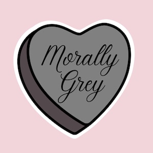 May include: A gray heart-shaped sticker with the words "Morally Grey" in elegant black script. The sticker has a white border and a dark gray shadow, set against a soft pink background.