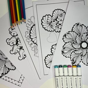 May include: Five black and white coloring pages with intricate designs, including a heart, a flower, and a butterfly. The pages are surrounded by a set of seven colorful markers.