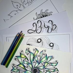 May include: A selection of detailed black and white line art designs on white paper, alongside a completed mandala in green and blue. Three coloured pencils in blue and green tones are positioned on the left.