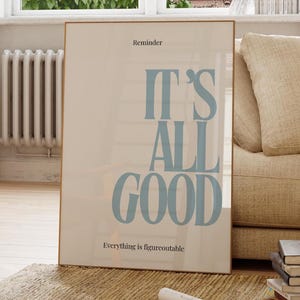 Könnte beinhalten: Ein gerahmtes Poster mit den Worten "IT'S ALL GOOD" in Hellblau, mit dem Text "Reminder" oben und "Everything is figureoutable" unten. Das Poster lehnt an einem beigen Sofa in einem hellen Raum.
