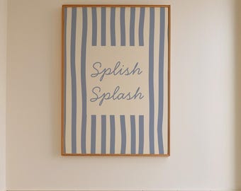 Könnte beinhalten: Badezimmer-Interieur mit einem gerahmten Druck mit blau-weißen Streifen und den Worten "Splish Splash". Ein Holzschemel hält eine Flasche und eine Bürste. Eine weiße Badewanne und ein Fenster sind ebenfalls zu sehen.