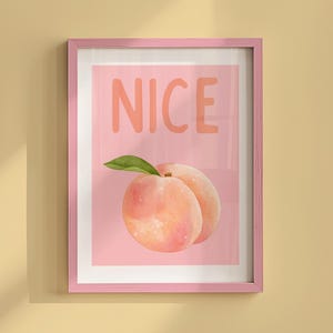 May include: A pink framed print with the word "NICE" in large white letters and a peach illustration.