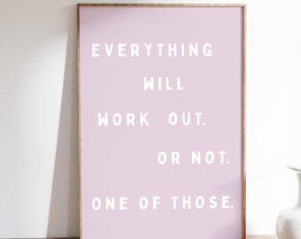 May include: A framed print with a light pink background and white text that reads "EVERYTHING WILL WORK OUT. OR NOT. ONE OF THOSE." The frame is a light brown color. The print is on a wooden desk.