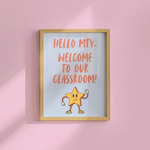 以下が含まれることがあります： オレンジ色の「HELLO MTV, WELCOME TO OUR CLASSROOM!」というテキストが入った額入りのポスター。ポスターには、腕と脚のある漫画の星のキャラクターが描かれています。フレームは薄茶色で、背景は薄いピンク色です。