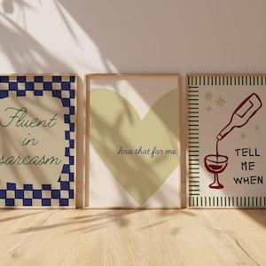 May include: Three framed art prints with a light wood finish. The prints feature text and graphics, including a blue and white checkered design with "Fluent in sarcasm", a green heart with "love that for me", and a wine-themed illustration.