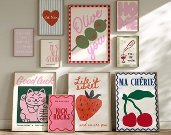 May include: A collection of framed art prints with various designs and text. Prints include a red heart, olives, a strawberry, a lucky cat, and the phrases "Olive you," "Home sweet home," and "Ma Chérie." The color palette includes pink, red, green, and blue.