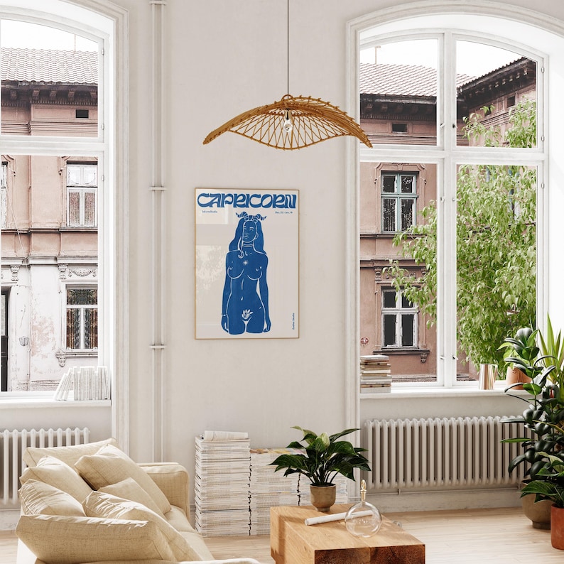 May include: A blue and white poster with the word "Capricorn" in bold, stylized letters. The poster features a blue silhouette of a woman with a crown of flowers on her head.