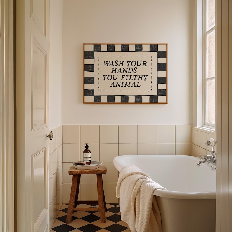 May include: A bathroom scene featuring a framed sign with the text "WASH YOUR HANDS YOU FILTHY ANIMAL." The sign has a black and white checkered border. A wooden stool holds a bottle and brush. A white bathtub and a checkered floor are also visible.