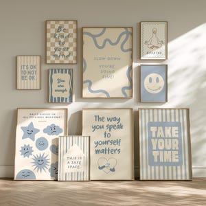 Puede incluir: Un conjunto de diez pósteres de pared con paletas de colores azul y beige, textos motivadores e ilustraciones de un ganso, caras sonrientes, estrellas, nubes y corazones. Las láminas muestran frases como Be kind to your mind, Breathe y Take your time.