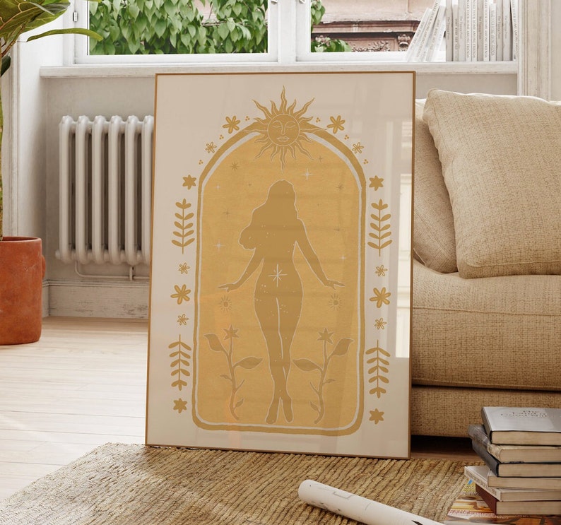 May include: A rectangular framed wall art print featuring a mustard yellow archway design. Inside the arch is a silhouette of a standing figure surrounded by a sun, stars, and floral motifs. The background of the print is a cream color.