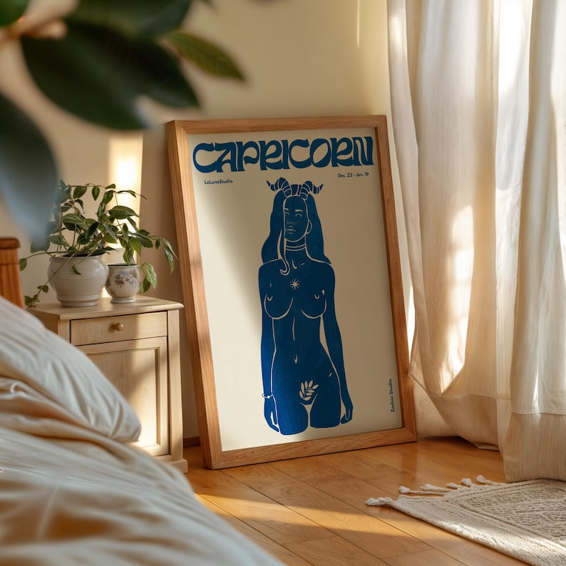 May include: A framed poster with a blue illustration of a woman with horns and a star on her chest. The poster has the text "Capricorn" and "Dec. 22 - Jan. 19" at the top.