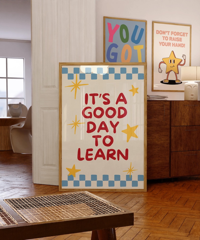 May include: A framed poster with the text "IT'S A GOOD DAY TO LEARN" in red, with yellow star accents and a blue and white checkered border. Two other framed posters are visible, one with "YOU GOT" and another with a cartoon star.