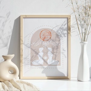 K&ouml;nnte beinhalten: Ein gerahmter Druck mit einem minimalistischen Design, das zwei Figuren zeigt, die sich unter einer gro&szlig;en, orange-roten Kugel gegen&uuml;berstehen. Die Figuren sind in Wei&szlig; umrandet und haben einen weichen, pfirsichfarbenen Hintergrund. Der Druck ist von einem hellen Holzrahmen umgeben.