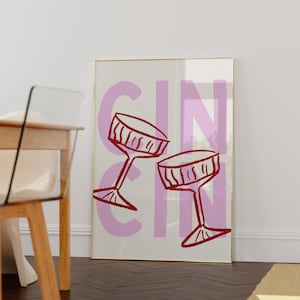 Puede incluir: Una impresi&oacute;n art&iacute;stica enmarcada con la palabra "GIN" en letras grandes de color lila. Dos copas de vino rojas est&aacute;n dibujadas en un estilo simple e ilustrativo. El fondo es de color crema claro.