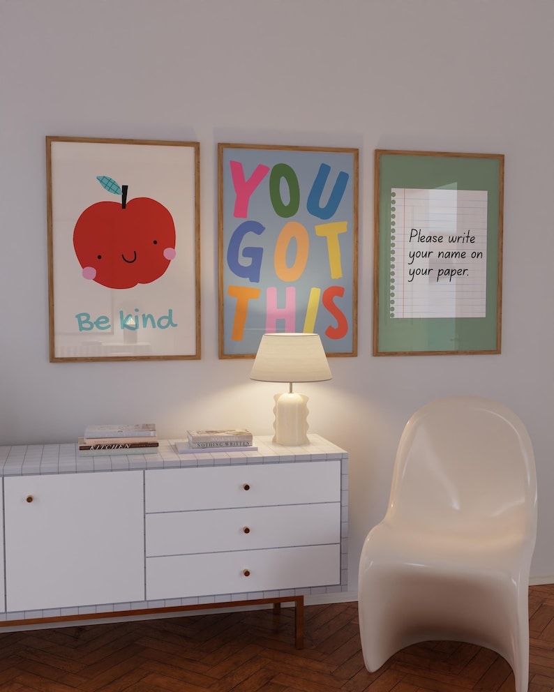 May include: Three framed art prints with positive messages. One features a red apple with the words "Be kind." Another says "YOU GOT THIS" in colorful letters. The third says "Please write your name on your paper."
