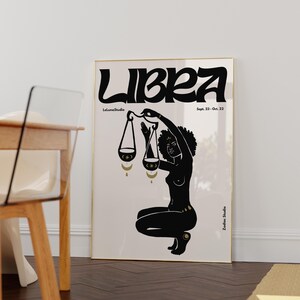 May include: Black and gold zodiac poster featuring Libra, the scales, with the dates September 23 - October 22. The poster features a black silhouette of a woman holding a scale with gold accents.