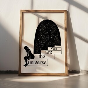 Puede incluir: Ilustraci&oacute;n en blanco y negro de una persona sentada en unos escalones con el texto "You are the universe" encima. El fondo es un arco negro con estrellas blancas.