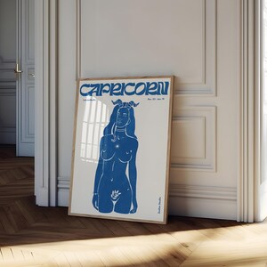 May include: Blue and white poster with a stylized illustration of a woman with horns and a star on her chest. The text "Capricorn Dec. 22 - Jan. 19" is at the top of the poster.