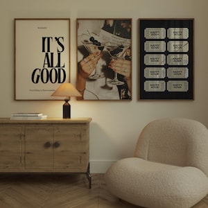 May include: Three framed wall art prints displayed above a wooden sideboard. The left print features the black text IT'S ALL GOOD on a cream background. The center print shows two martini glasses with cherries. The right print displays ten black and white Happy Hour tickets on a black background.