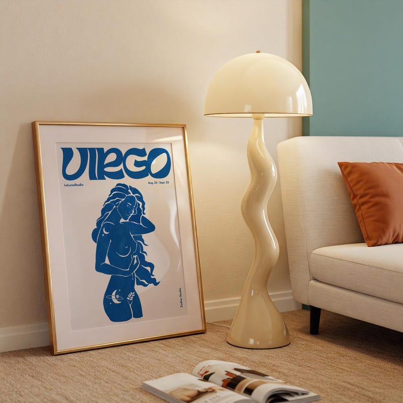 K&ouml;nnte beinhalten: Ein gerahmtes Poster mit einer blauen Illustration einer Frau, die das Sternzeichen Jungfrau darstellt. Das Poster hat einen goldenen Rahmen und liegt auf einem beigefarbenen Teppich. Der Text auf dem Poster lautet "Virgo" und "23. August - 22. September".