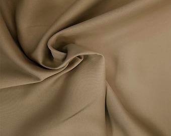 May include: A close-up of a smooth, light brown fabric with a soft, drapey texture.