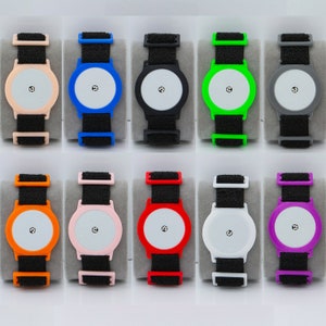 May include: Ten colourful wristbands with a round, white face and a black dot in the centre. The wristbands are made of a flexible, rubber-like material and come in a variety of colours, including black, blue, green, orange, pink, purple, red, white, and yellow.