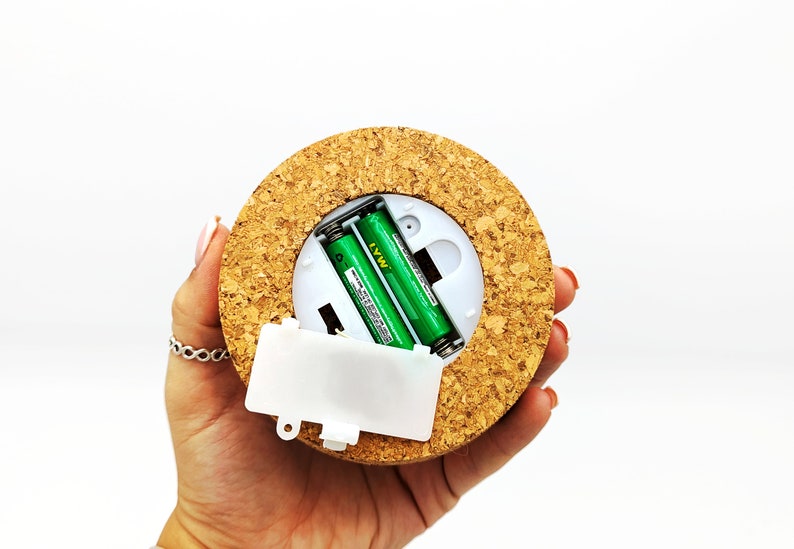 Peut inclure: Une lumi&egrave;re ronde recouverte de li&egrave;ge avec un compartiment &agrave; piles en plastique blanc et deux piles AA vertes &agrave; l'int&eacute;rieur.