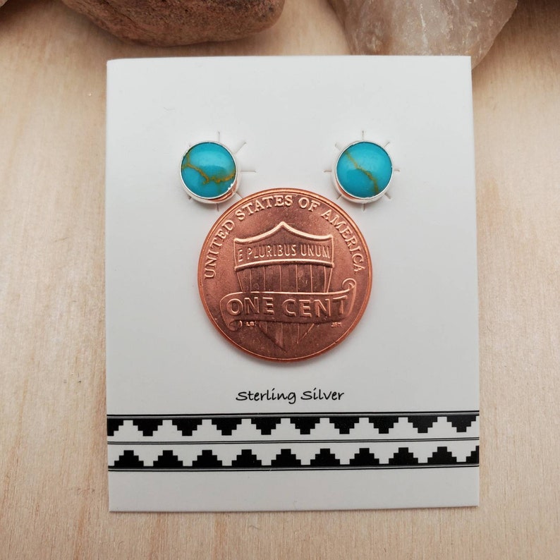 May include: A pair of sterling silver earrings with turquoise stones, shown next to a US penny for size comparison.  Sterling Silver.