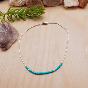 May include: A silver chain necklace with a magnetic clasp and turquoise beads.