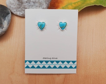 Puede incluir: Un par de pendientes de plata de ley en forma de corazón con piedras turquesa. Los pendientes están en una tarjeta blanca con el texto "Sterling Silver" impreso en ella.