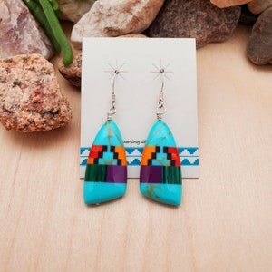 May include: A pair of turquoise and multi-colored stone earrings with sterling silver hooks. The stones are set in a geometric pattern and are surrounded by a silver bezel.
