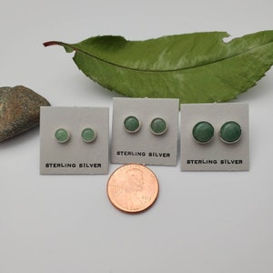 May include: Three pairs of sterling silver earrings with green gemstone studs. The earrings are displayed on white cards with the words "Sterling Silver" printed on them. A penny is included for size reference.