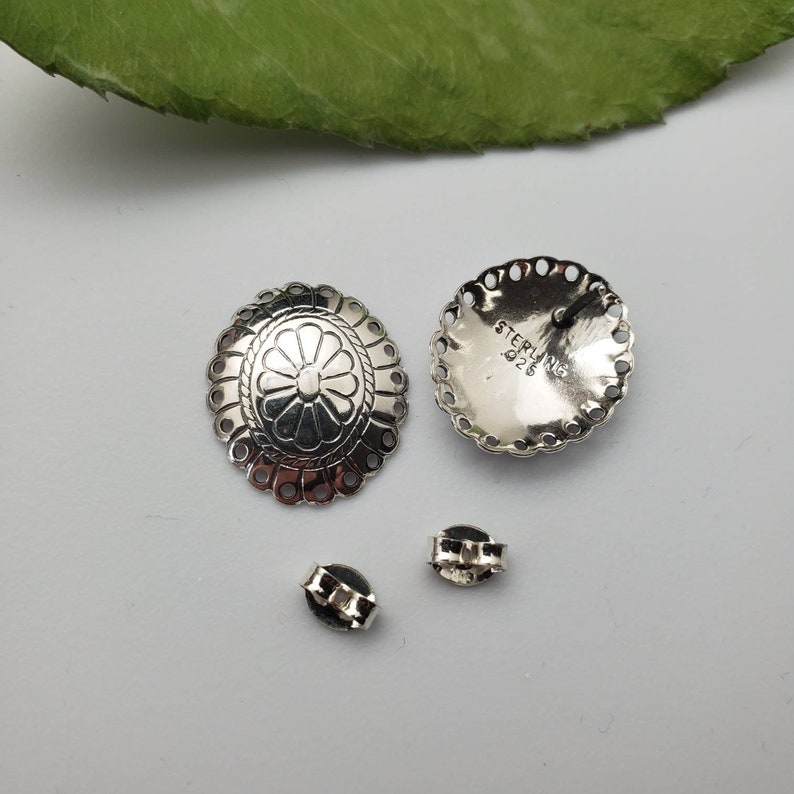 May include: A pair of silver earrings with a floral design. The earrings are marked "STERLING 925" on the back.