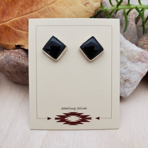 May include: A pair of black onyx earrings with sterling silver settings. The earrings are shaped like diamonds and are displayed on a white card with the text "Sterling Silver".