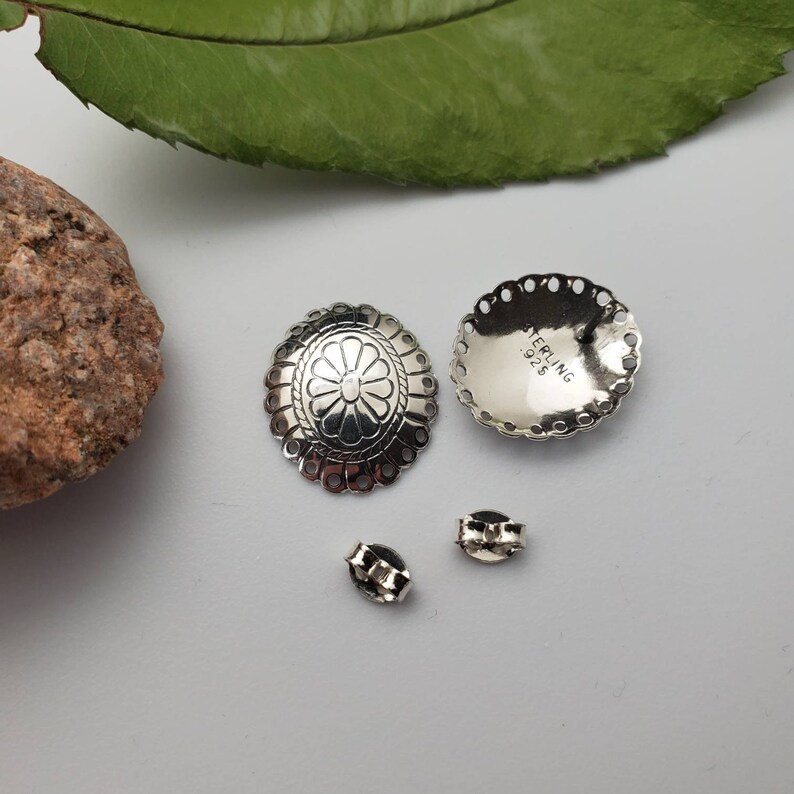 May include: A pair of silver earrings with a floral design. The earrings are marked "STERLING 925".