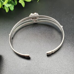 Op de afbeelding: Zilveren armband met een decoratieve, veelkleurige steen in het midden.