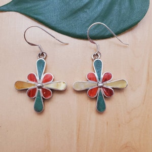 May include: A pair of silver earrings with a flower design. The flower is made of red, yellow, and green stones.