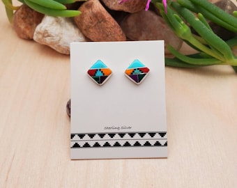 May include: A pair of sterling silver earrings with a geometric design featuring turquoise, red, orange, yellow, green, and purple stones. The earrings are displayed on a white card with the text "sterling silver".
