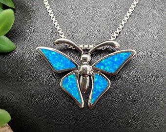 May include: A silver chain necklace with a blue opal butterfly pendant. The butterfly has a detailed design with intricate wings.