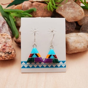 May include: A pair of sterling silver earrings with a triangular design. The earrings are inlaid with turquoise, purple, green, red, and black stones.